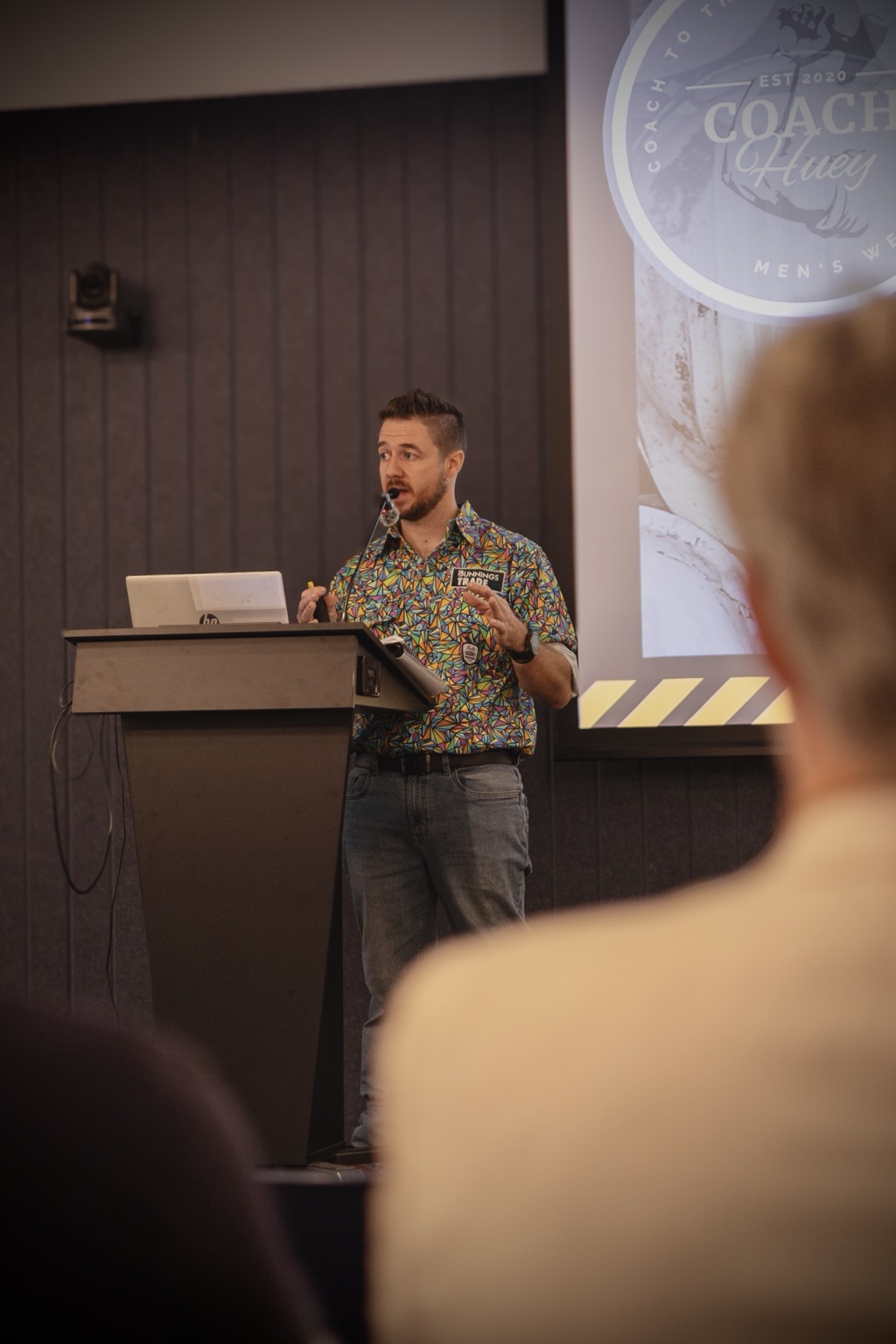 Aaron speaking at a lectern during a wellbeing presentation